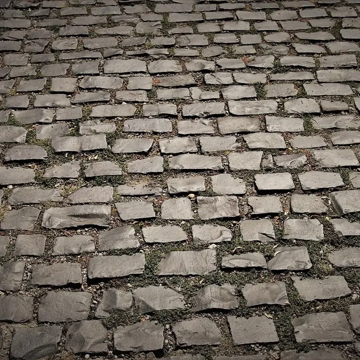 A cobbled road made from uneven, grey, roughly stone bricks