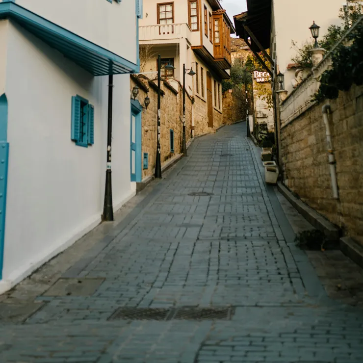 A steep road with terraced houses on the left, and a path on the right, with a hand rail going part of the way up the hill.